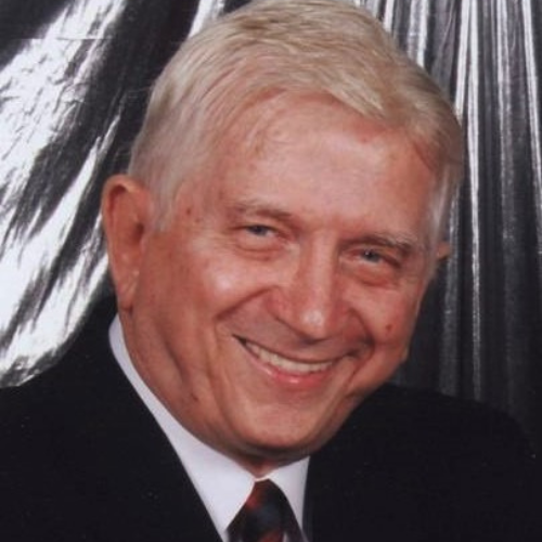 A man with white hair and wearing a suit.